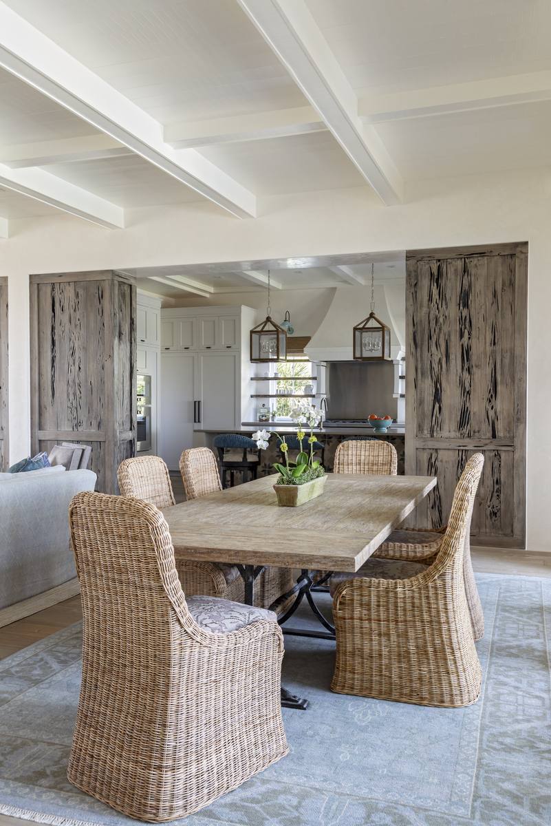 Open-concept dining and kitchen with reclaimed pecky cypress door and stain-grade ceiling beams, Sullivan's Island custom waterfront home