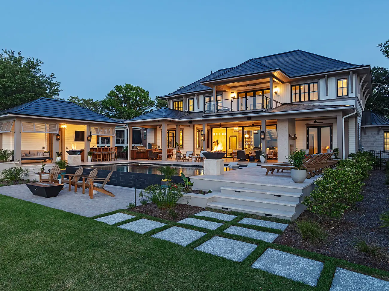 Rear exterior at dusk with pool and stepping-stone lawn, James Island Contemporary home